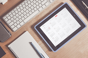 A tablet with a calendar with a keyboard on a desk